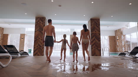 joyful-weekend-in-family-wellness-center-father-mother-and-two-children-are-going-to-indoor-pool